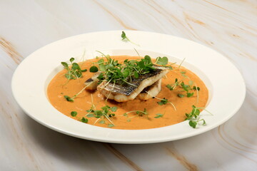 fried sea bass fillet on a vegetable sauce decorated with sprouts. Fried sea fish 