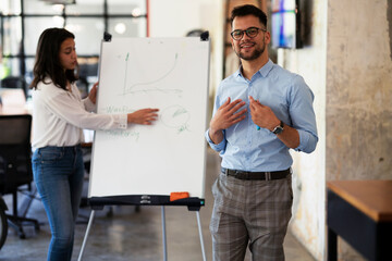 Businessman present his idea to working team. Young happy man presenting businessplan.