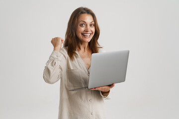 European ginger woman making winner gesture while using laptop