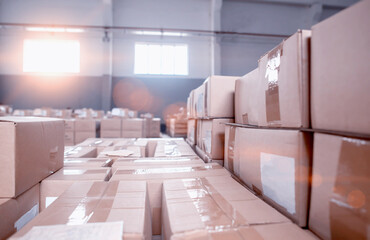 Warehouse with cardboard boxes in storage. The sunset shines through the windows, background