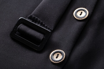 Black stylish clothes with buttons and a belt, background. Dress for woman, macro, material