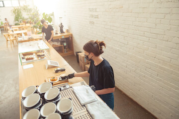 Woman in mask working barista in coffeehouse