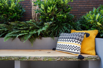 Cozy seating, Wooden sofa with colorful pillows in cozy garden seat, green plants and modern...