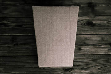 mockup empty craft trapezoidal cardboard box on an old wooden table close up. tinted in black color. top view, flat lay and space for text