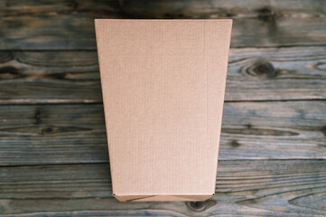 mockup empty craft brown trapezoidal cardboard box on an old wooden table close up. top view, flat lay and space for text