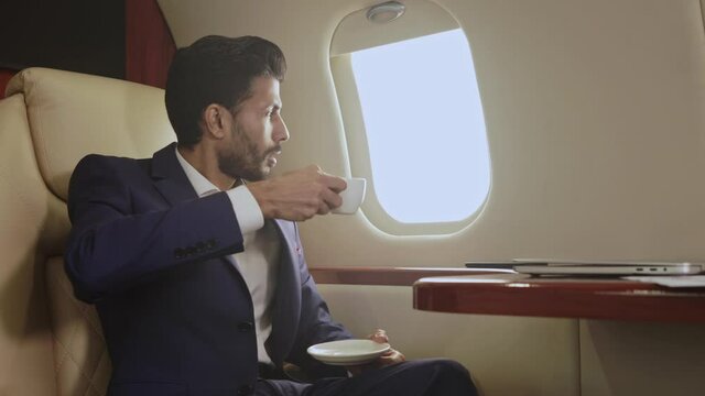 Man flying in the private jet and drinking coffee.