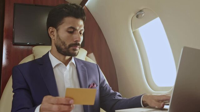 Man doing online payment, using credit card, sitting in the airplane.
