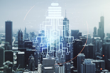 Double exposure of virtual creative light bulb hologram with chip on Chicago city skyscrapers...