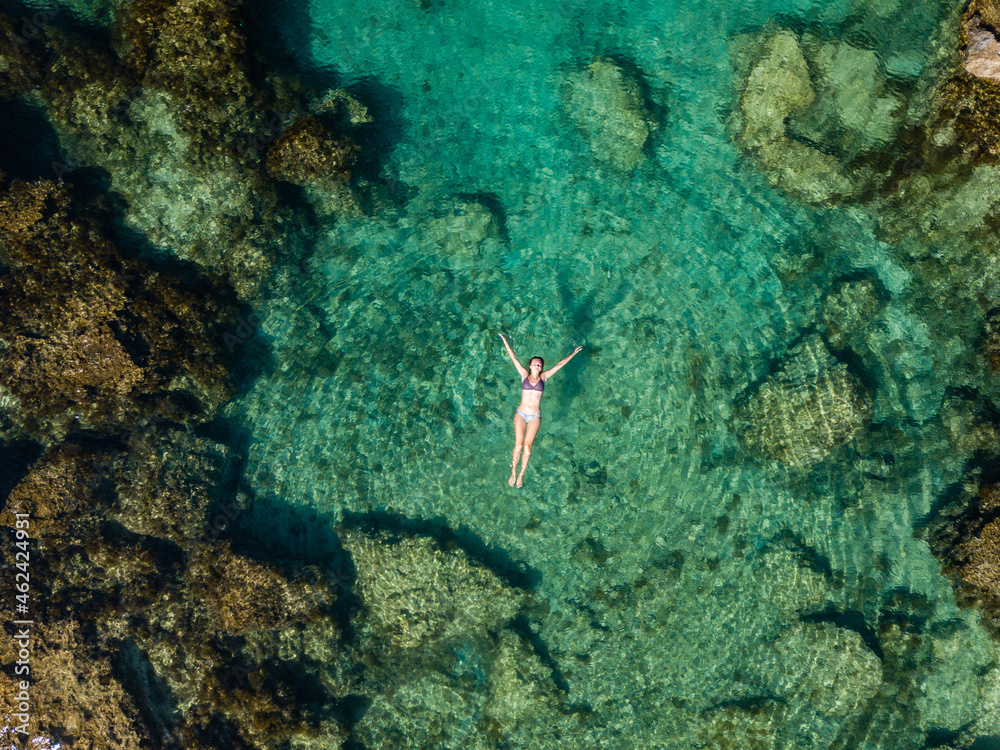 Wall mural aerial view of swimming woman in clear water of mediterranean sea.