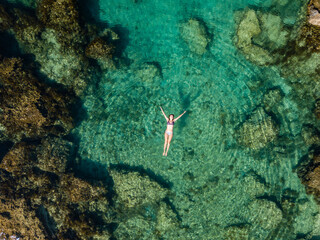 Aerial view of swimming woman in clear water of Mediterranean Sea.