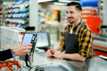 Woman hand making a contactless payment with her smartphone at a supermarket