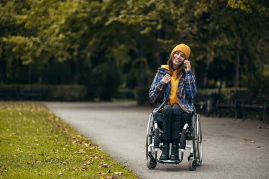 Woman in wheelchair using a smartphone while out in the city park