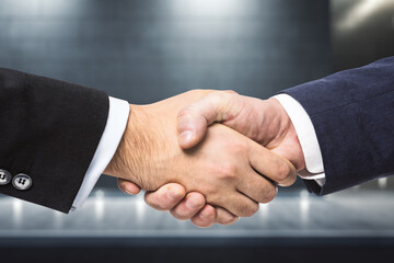Obraz premium Handshake of two businessmen on the background of night exterior of the business center, partnership concept, close up