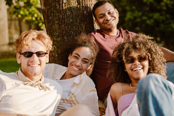 Multiracial young students smiling together while resting on grass