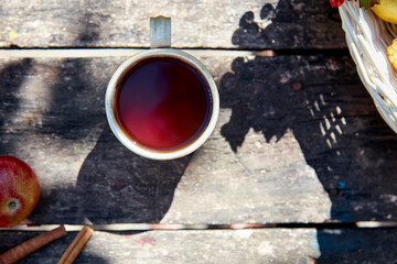 Cup of tea on wooden background in rustic style with trendy natural shadows. Top view, copy space. Viburnum and cinnamon sticks. Autumn aesthetic still life. Thanksgiving Day concept.