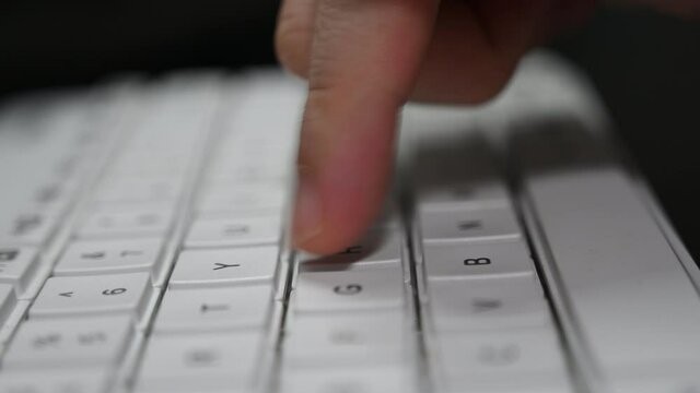 A man is typing on a bluetooth Logitech keyboard.