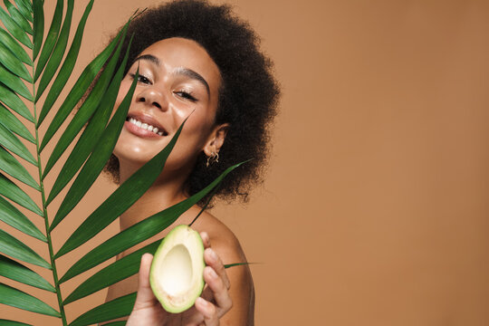 Black Shirtless Woman Smiling While Posing With Avocado And Plant