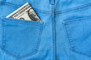 One dollar in the back pocket of denim trousers