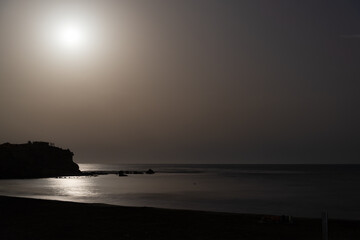 Night picture of a beach of Aguilas, Murcia, Spain. The moon is reflecting over the rippled waters of mediterranean. Dark cliff on the left.
