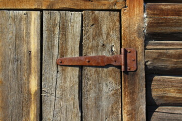 Wooden Fence Door View with Weathered Wall Planks, Old Rusty Hinges and Chains. Agricultural Livestock Building Tree Texture Background