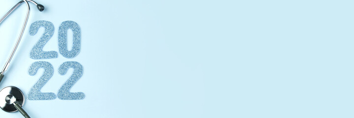 Stethoscope with 2022 blue number on blue background. Happy New Year for healthcare and medical banner or calendar cover. Horizontal long banner for web design with copy space