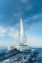 Luxury catamaran sailing under white sails on the blue azure sea on a sunny summer day. Travel, yachting, regattas concept - obrazy, fototapety, plakaty