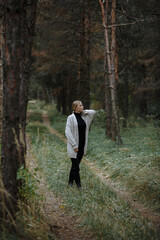 Fototapeta na wymiar girl in black golf with a gray cape among the autumn forest