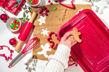 Christmas, New Year cooking background. Baking ingredients and utensils - gingerbread dough, cookie cutters, rolling pin. Woman hands making festive Xmas sweet cookies bright festive red white concept