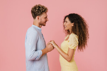 Young white couple holding hands while smiling at camera