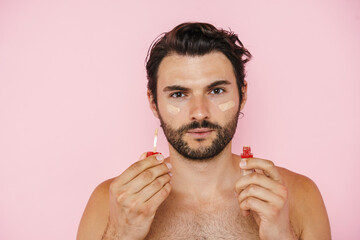 Young half-naked man showing and applying foundation