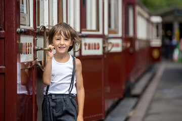 Beautiful child, dressed in vintage clothes, enjoying old steam train on a hot summer day