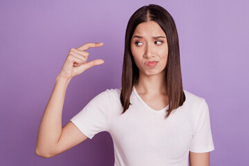 Photo of young girl unhappy sad hesitate doubt show fingers little small tiny size measure isolated over violet color background