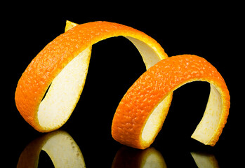 Spiral orange zest on a black background. Citrus twist peel. Citrus fruit.