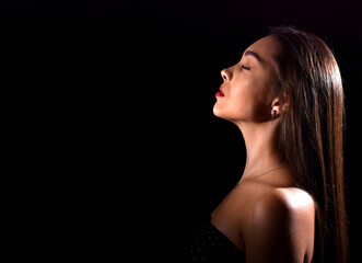beautiful young woman with luxurious makeup and bare shoulders. Black background with space for text