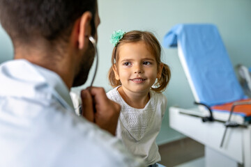 Fototapeta premium Doctor examines a child with stethoscope in examination room. Healthcare people children concept