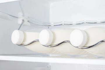 three bottles of farm milk on a shelf in the refrigerator, close-up