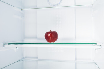 red apple on a glass shelf in the refrigerator