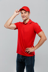Young delivery man wearing red hat smiling and looking at camera