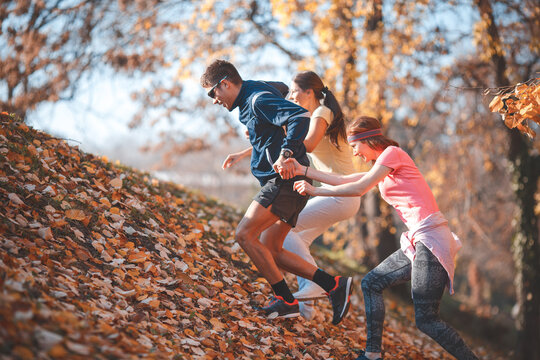 Group of friends in sportswear jogging at the park on beautiful day.Autumn concept.	

