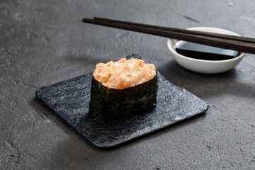 close up view of maki sushi rolls with chopsticks on grey stone table
