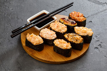 tempura sushi rolls on wooden plate served with soy sauce and chopsticks