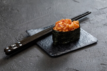 close up view of maki sushi rolls with chopsticks on grey stone table