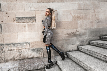 High fashion. Sexy woman in elegant outfit and fashionable boots is posing in the city. Fashion...