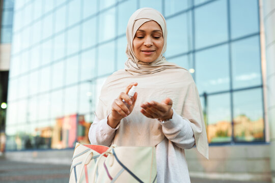 Middle eastern muslim woman in hijab applying sanitizer