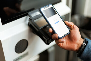 Man using mobile phone while buying ticket at station
