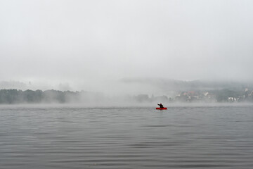 Fisherman in a boat early morning on the lake Lipno in the mountains Sumava, Czech Republic