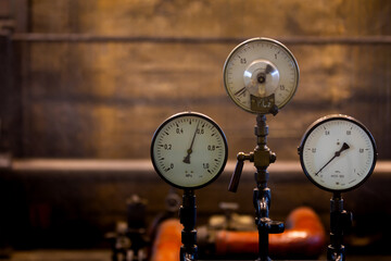 Old analog pressure gauges on an industrial steam plant. Photo taken in low light conditions,...