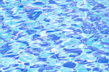 Fototapeta na wymiar Ripple Water in swimming pool with blue tile floor background