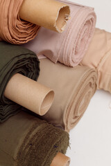 Stack of pastel color fabric rolls of synthetic and natural fabrics