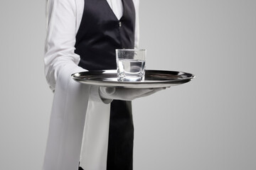 Crop waiter with glass of water on tray